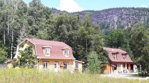 deux maisons dans un champ planté d'arbres en arrière-plan dans l'établissement Grangette Entre Chiens et Loups, à LʼAnse-Saint-Jean