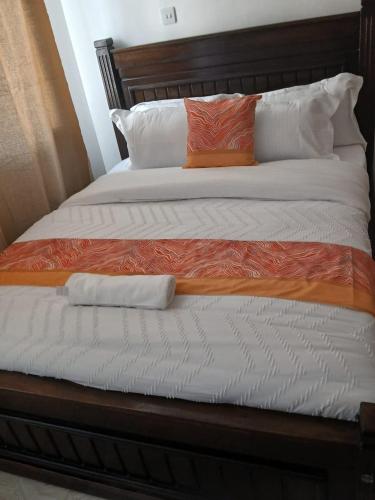 a bed with an orange and white comforter and pillows at Machakos Town 3 Bedroom Ensuite in Machakos