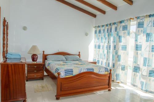 a bedroom with a bed and a dresser and curtains at Arla Residential in Mindelo