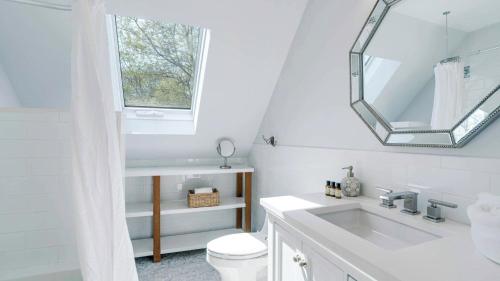 a white bathroom with a sink and a mirror at Villa Mist Manor in East Hampton