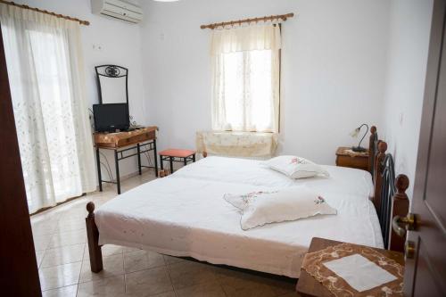 a bedroom with a bed and a desk and windows at Lesvos Garden Retreats - Mountain Voyage Residences in Vatoússa