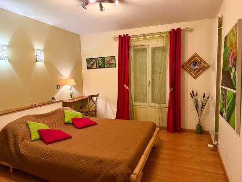 a bedroom with a bed with green and red pillows at Le Domaine de Rose in Lourdes