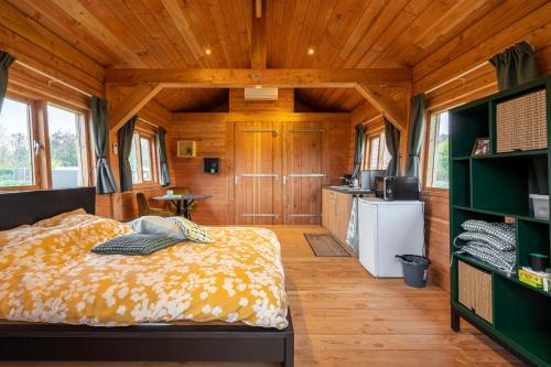 a bedroom with a bed and a kitchen in a cabin at Vakantiehuisje Appel & Fleur in Swalmen