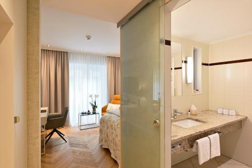 a bedroom with a bed and a bathroom with a sink at Kastens Hotel Luisenhof in Hannover