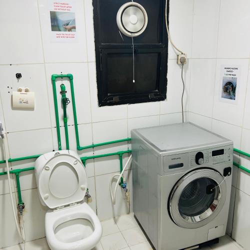 a bathroom with a washing machine and a toilet at Universe Holiday Homes in Dubai