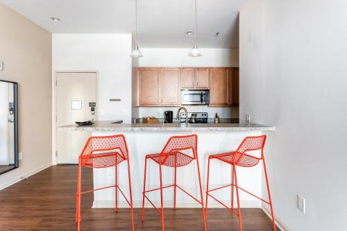 a kitchen with three orange stools at a counter at Mint House Greenville Downtown By Kasa in Greenville