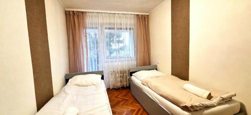 two beds in a small room with a window at Levu Lak in Kapuvár