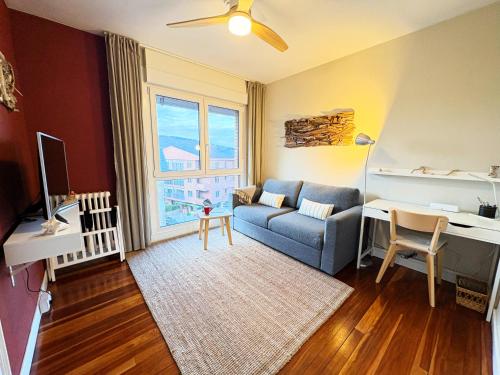 a living room with a blue couch and a desk at Casa Carlini in Getxo