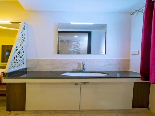 a bathroom with a sink and a mirror at IVY RESIDENCY in Coimbatore