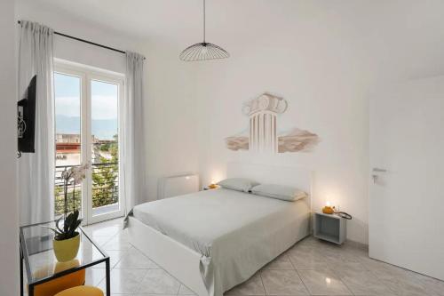 a white bedroom with a bed and a large window at GRIMALDI ROOMS Costa d'Amalfi in Pagani