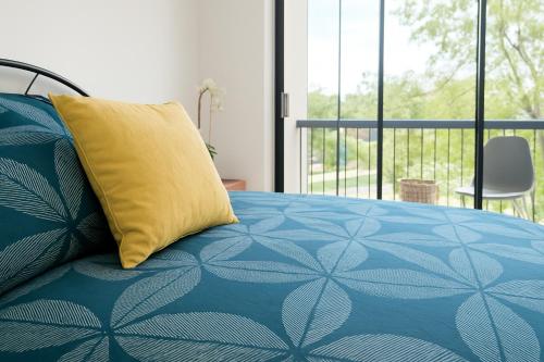 a bed with a yellow pillow on top of it at Deluxe Himeji 2 Bedrooms Apartment in Adelaide
