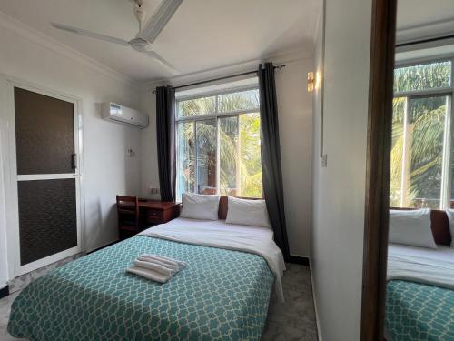 a bedroom with two beds and a window at PhyllenHotel Tanga in Tanga