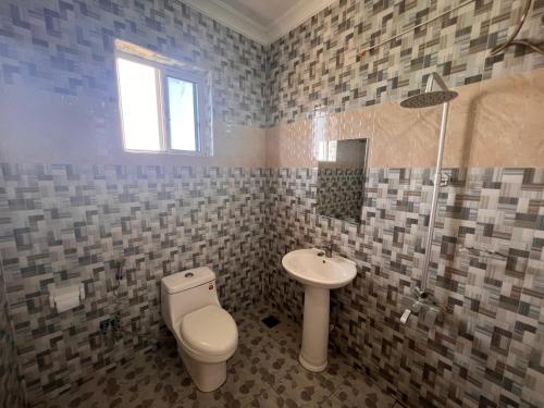 a bathroom with a toilet and a sink at PhyllenHotel Tanga in Tanga