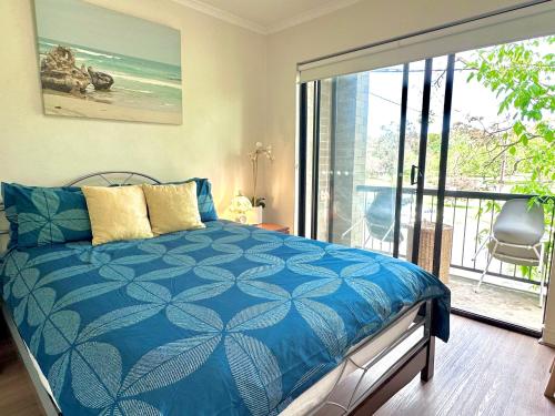 a bedroom with a blue bed and a balcony at Deluxe Himeji 2 Bedrooms Apartment in Adelaide