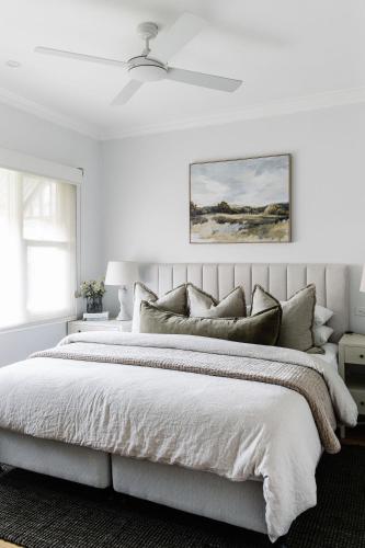 a white bedroom with a large bed with a ceiling fan at Corner Cottage Bright in Bright