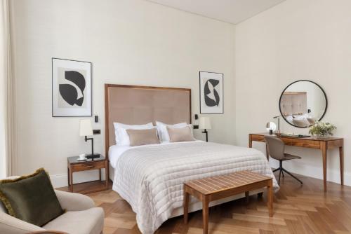 a bedroom with a bed and a chair and a mirror at The Queens Gate Hotel in London