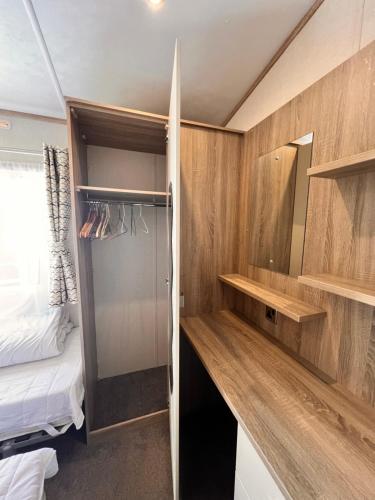 a small room with a bed and a closet at Swanage Luxury Caravan - Stunning sea views, Large decking area, Free EE WIFI, Sleeps 6, Pet Friendly on Swanage Bay View Holiday Park in Swanage
