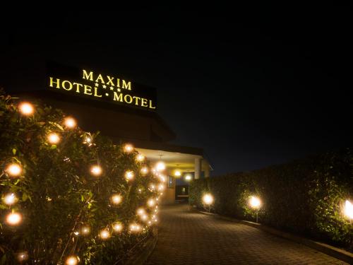 a building with a sign for a hotel at night at Hotel Maxim in Peschiera Borromeo