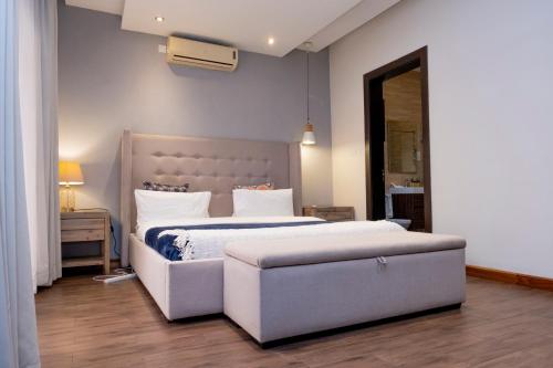 a bedroom with a large white bed and a couch at Fallsway Palms in Lusaka