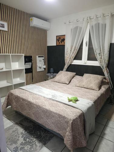 a bedroom with a bed with a green frog sitting on it at Tortue marine in Saint-Benoît