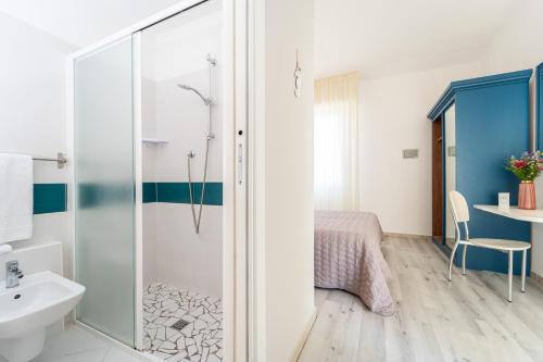 a bathroom with a shower and a bed and a sink at Amadei Hotel Promenade in Pesaro