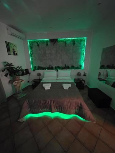 a bedroom with a large bed with green lighting at Monreale Prestige Rooms B&B in Monreale