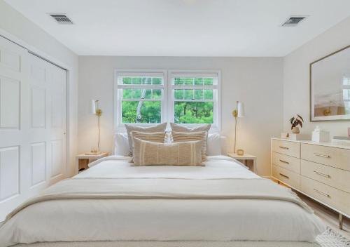 a white bedroom with a large bed and a window at Villa Montauk Mist in East Hampton