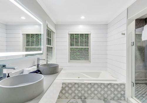 a white bathroom with a tub and a sink at Villa Montauk Mist in East Hampton