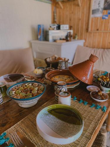 a table with bowls and plates of food on it at Dania Surf House in Mirleft