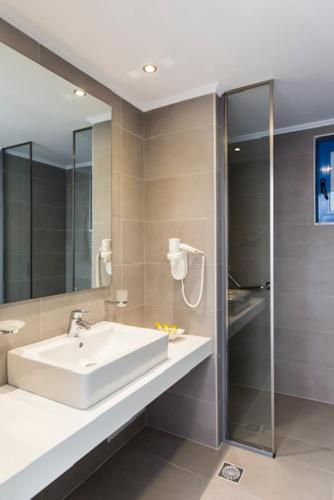 a bathroom with a sink and a glass shower at Lindos Portes Blue in Lindos