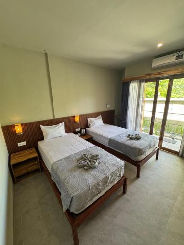 a bedroom with two beds and a large window at Hepy Hotel in Kuta Lombok