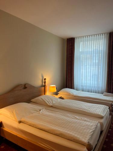 two beds in a hotel room with a window at Hotel Kronprinz Garni in Minden