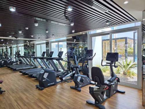 a gym with rows of treadmills and elliptical machines at Vogue Vacation Homes, Al Furjan Pearlz by Danube near Ibn Battuta Mall, One Bedroom Apartment with Terrace and vibrant community view, Access to all Amenities, Walkable to Al Furjan Metro Station in Dubai