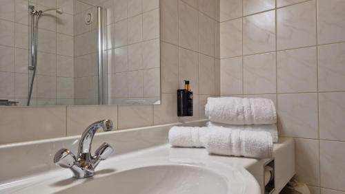a bathroom with a sink and towels on a tub at Hotel Dahoam by Miha in Westendorf