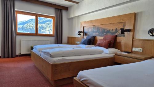 a hotel room with two beds and a window at Hotel Dahoam by Miha in Westendorf
