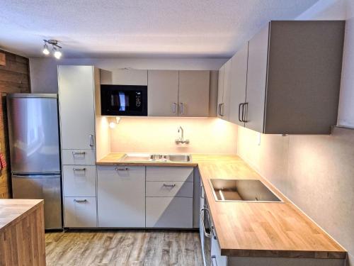 a kitchen with white cabinets and a stainless steel refrigerator at Holiday Home Ötztal by Interhome in Oetz