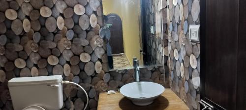 a bathroom with a toilet and a wall of logs at Sea view Sun shine in Calangute