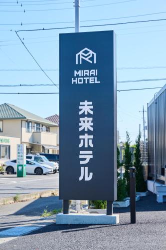 a sign for a hotel on the side of a street at 未来ホテル 伊勢崎 MiraiHotel Isesaki in Isesaki