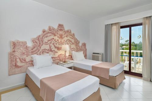 a hotel room with two beds and a balcony at Hotel Apartamento Do Golfe in Vilamoura