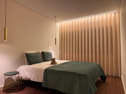 a bedroom with a bed with a teddy bear sitting on it at Music Apartment II in Bicas