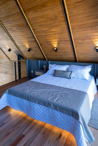 a large bed in a room with a wooden ceiling at Cabanas Horizonte Cambará Nature in Cambará