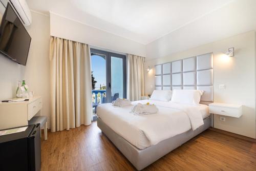a bedroom with a large white bed and a large window at Hotel Santa Eulália Bay in Albufeira