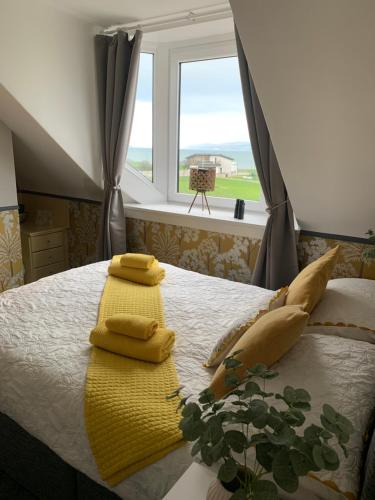 a bedroom with a bed with yellow towels and a window at Neptunes Rest Guest Hotel in Stranraer