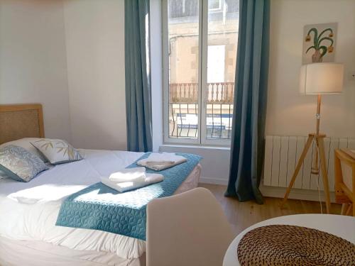 a bedroom with a bed and a window with blue curtains at Le 16 Place de l'Abbatiale in Évron