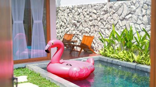 a pink inflatable swan sitting in a swimming pool at Among Villa in Yogyakarta