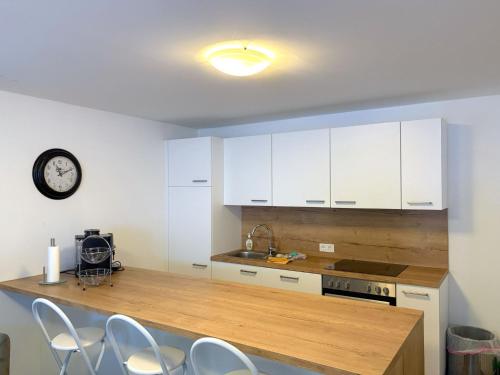 a kitchen with white cabinets and a counter with chairs at Apartment Benjamin by Interhome in Hollersbach im Pinzgau