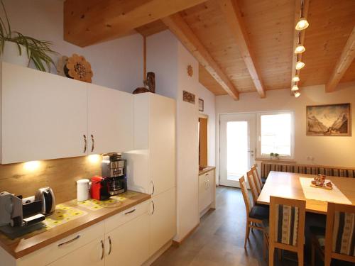 a kitchen with white cabinets and a table and a table and a dining room at Holiday Home Bergblick by Interhome in Kappl