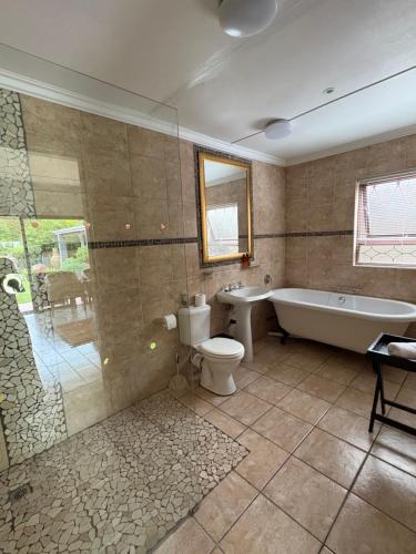 a bathroom with a tub and a toilet and a sink at Mountain Dew Guest House in George