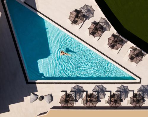 a person swimming in a pool with umbrellas at Nimfi Suites in Skiathos