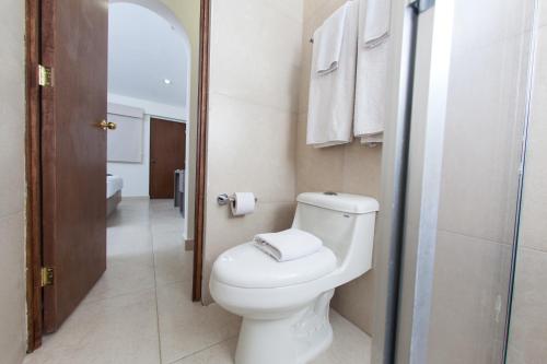 a bathroom with a toilet and a shower with towels at Hotel La Riviera in Culiacán